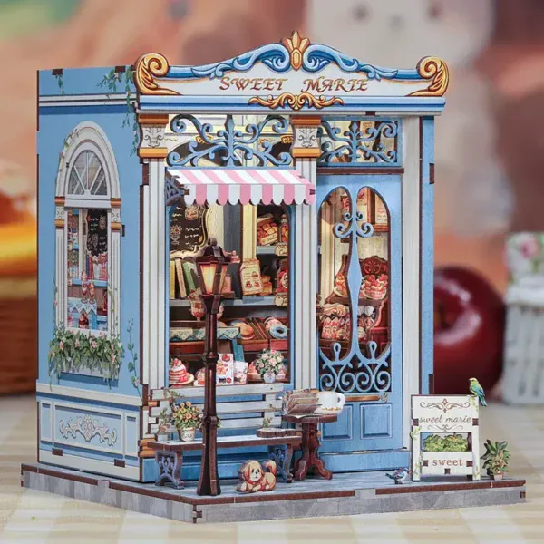 Детайл от миниатюрен сладкарски магазин "Sweet Marie" с цветна фасада и украса.